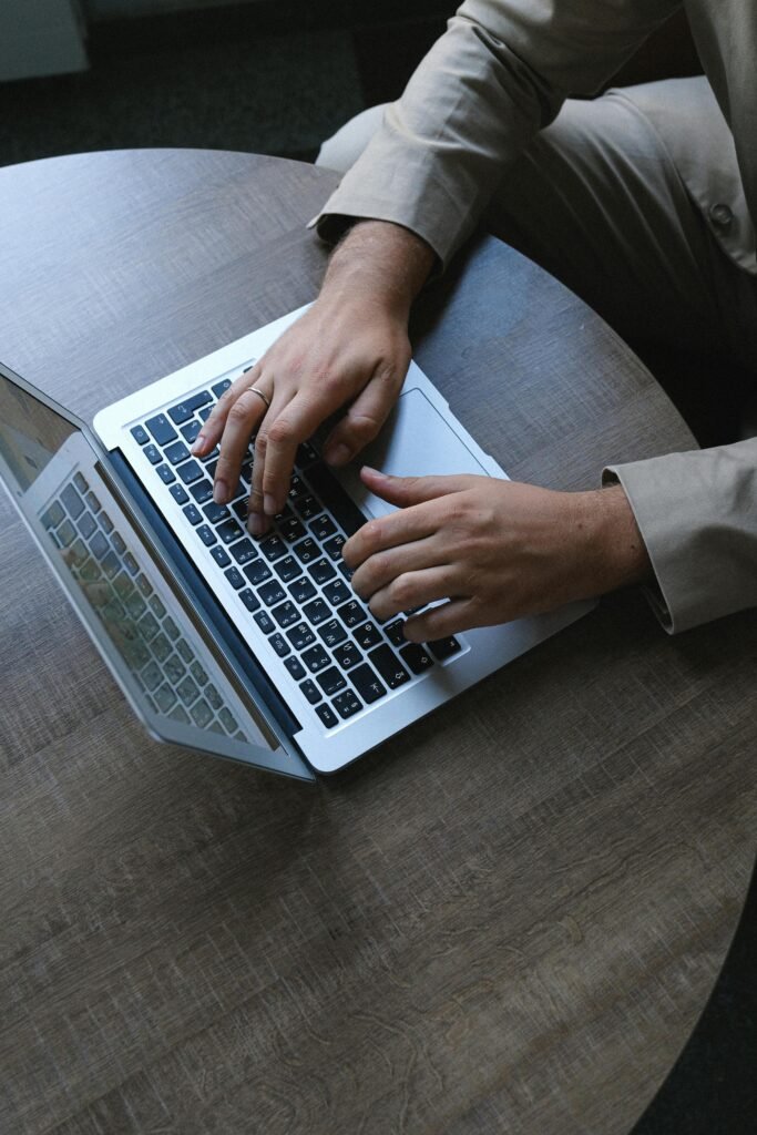 Adult male typing on a laptop indoors, showcasing a business environment and workspace.